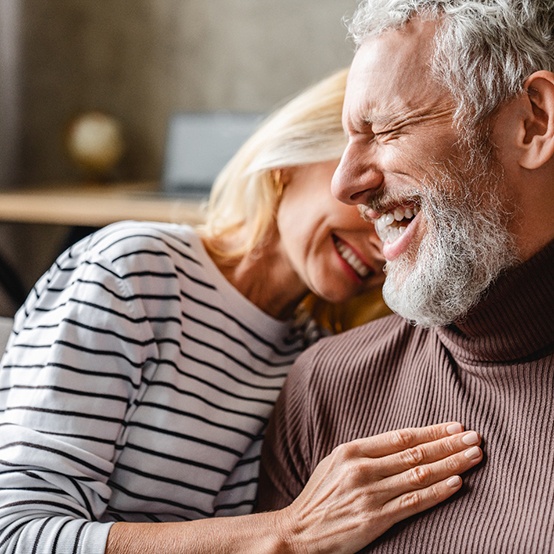 Laughing older couple sitting on sofa