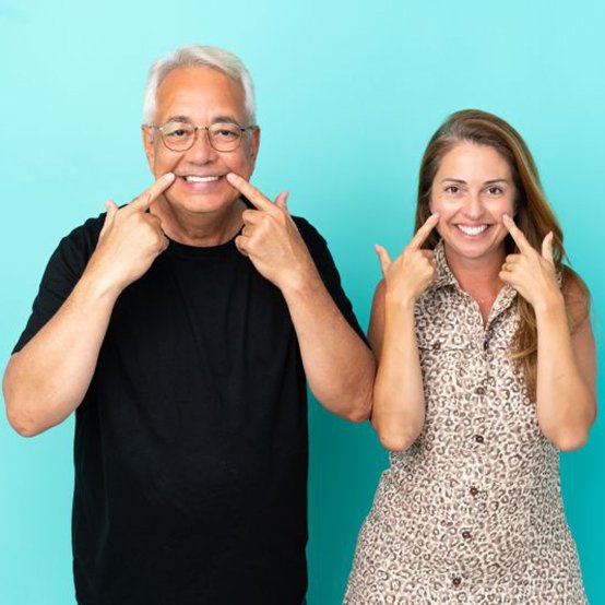 Happy middle-aged couple pointing at their smiles