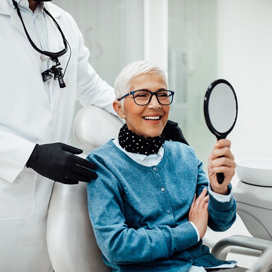 Senior woman admiring her smile after successful dental implant salvage