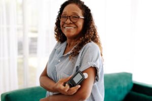 Smiling woman with diabetes holding her blood glucose monitor 